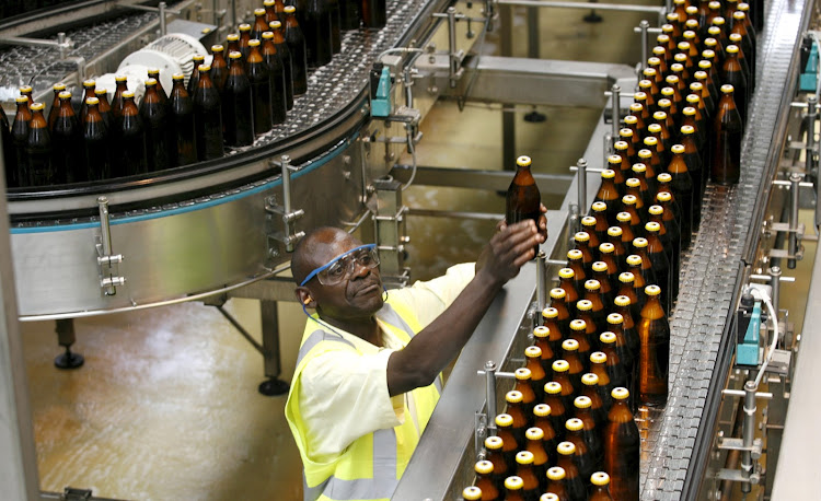 A worker inspects beer bottles on a conveyor belt at the East African Breweries Ruaraka factory