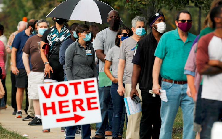 Voters wait in line to enter a polling place and cast their ballots on the first day of the state's in-person early voting for the general elections in Durham, North Carolina on US October 15 2020.