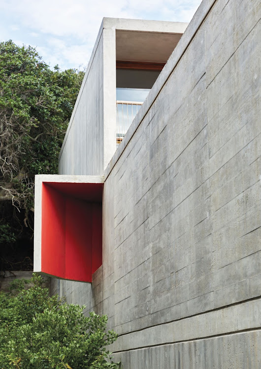 On either side of the exterior, a pair of asymmetrically placed “ears” draw light, views, and sea air into the two bedrooms placed at the rear of the central floor — and painting the insides of the “ears” in a bold red shade has given them strong visual appeal as “punctuation” points, in addition to emphasising their usefulness.