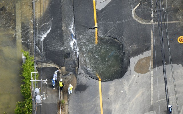 Water flows out from cracks in a road damaged by an earthquake in Takatsuki, Osaka prefecture, western Japan, in this photo taken by Kyodo June 18, 2018.