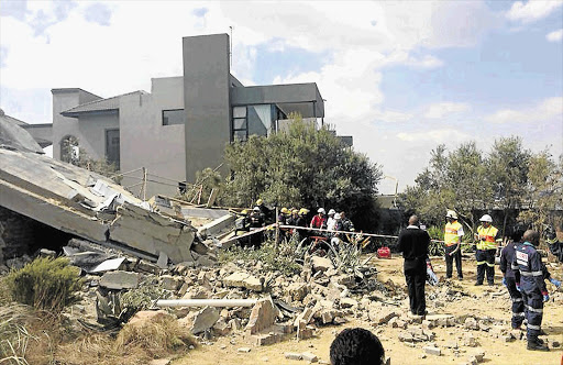 RUINED: Emergency and medical services personnel remove some of the bodies trapped under the rubble of a double-storey house in Meyersdal Eco Estate, south of Johannesburg, that collapsed yesterday morning. The death toll stood at seven last night