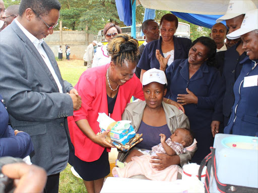 SMILE FOR US: Murang'a county executive for health Susan Magada presents a gift hamper to one of the mothers whose child was vaccinated with the new Inactivated Polio Vaccine as the Director of Medical services Jackson Kioko watches on at Ihura stadium on Thursday. Photo/Alice Waithera