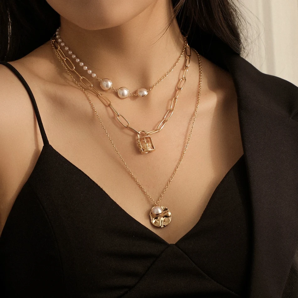 Drievoudige elegante ketting met parel- en schelpbedel, perfect voor een stijlvolle uitstraling en om de halslijn te accentueren.