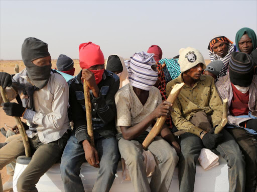 Migrants crossing the Sahara desert into Libya sit on the back of a pickup truck outside Agadez, Niger, May 9, 2016. Picture taken May 9, 2016. /REUTERS