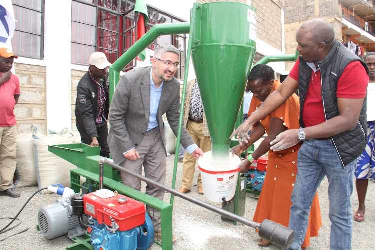 Turkish Cooperation and Coordination Agency Country director Eyup Yavuz Umuhu and Ahadi Kenya Trust CEO mill maize while handing over five posho mills to 200 beneficiaries in Murang'a on July 23, 2022.