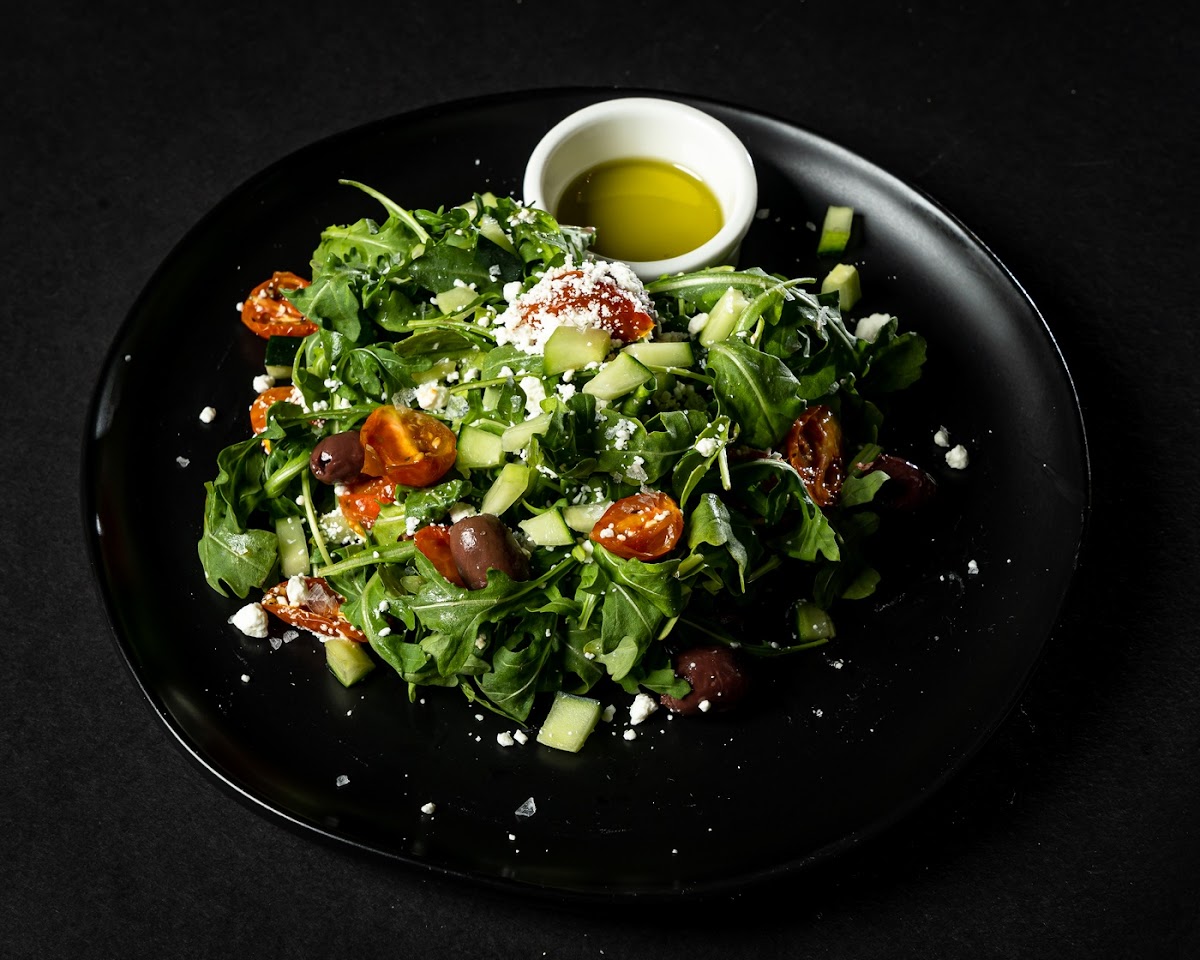 Aristotele salad with arugula, goat cheese, marinated cherry tomatoes, Kalamata pitted olives, cucumbers and olive oil.