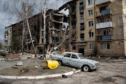 A damaged car is seen next to a heavily damaged apartment building on April 6, 2022 in Hostomel, Ukraine. 