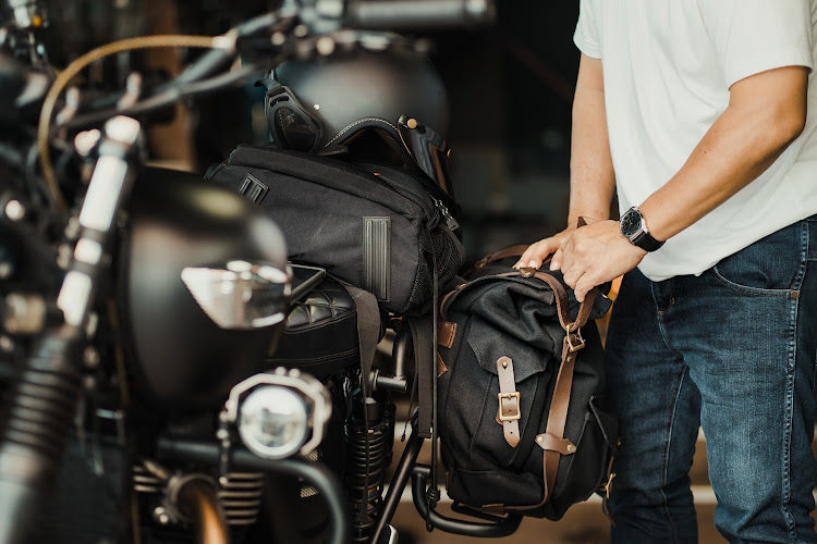 Rider installs a motorcycle saddlebag on luggage bracket vintage motorbike.