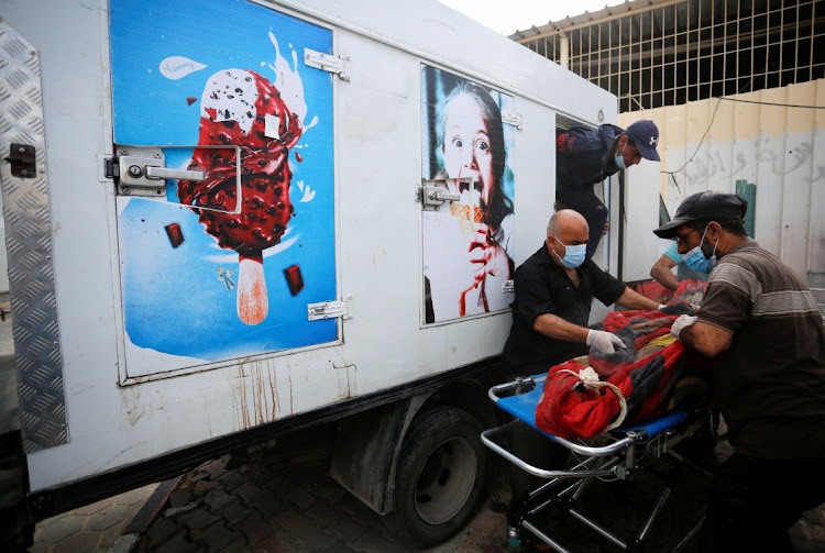 People move the body of a Palestinian, who was killed in Israeli strikes, from an ice cream truck where it was kept, as the hospital morgues are packed, amid the ongoing Israeli-Palestinian conflict, in the central Gaza Strip October 15, 2023.