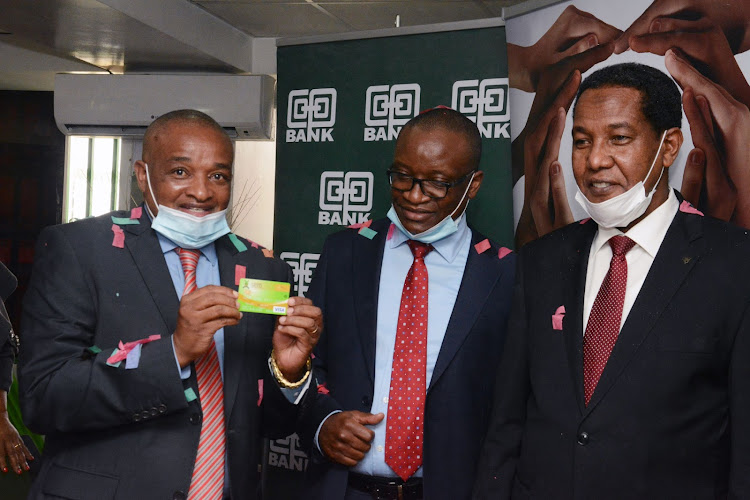 L-R) The Chairman Harambee Sacco Macloud Malonza displays the very first debit card printed and issued instantly at the Sacco, witnessed by the Director Cooperatives Banking at Co-op Bank Vincent Marangu and Principal Secretary, State Department for Cooperatives Ali Noor Ismail looking on./COURTESY