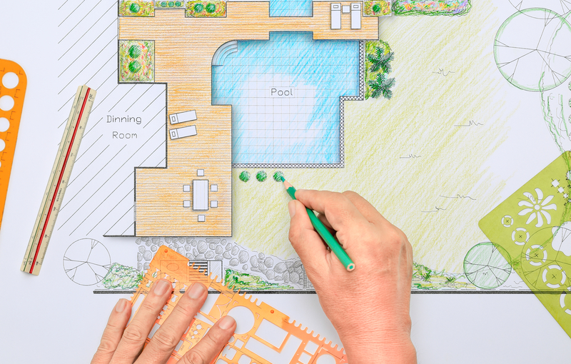 A professional sketches out a custom pool for a customer deciding between  fiberglass vs. concrete pool designs.