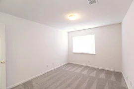 Bedroom with neutral carpeting and walls, window with blinds, and central light fixture