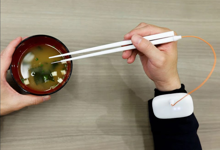 An employee of Kirin Holdings demonstrates chopsticks that can enhance food taste using an electrical stimulation waveform that was jointly developed by the company and Meiji University's School of Science and Technology Professor Homei Miyashita, in Tokyo, Japan April 15, 2022.