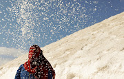 A woman is seen behind salt crystals as she visits the small salt hills in the canal city of Port Fouad, Egypt March 12, 2021.  