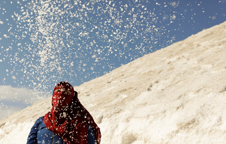 A woman is seen behind salt crystals as she visits the small salt hills in the canal city of Port Fouad, Egypt March 12, 2021.