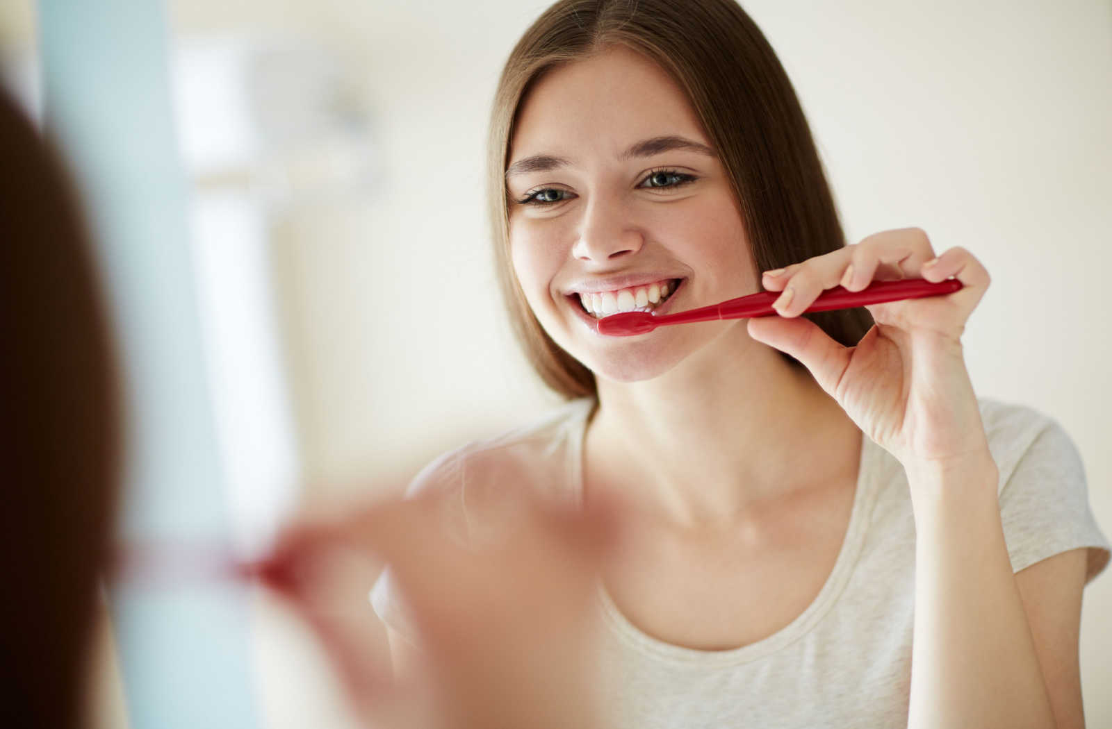 A woman uses fluoride toothpaste to brush her teeth twice daily and avoid tooth cavities.