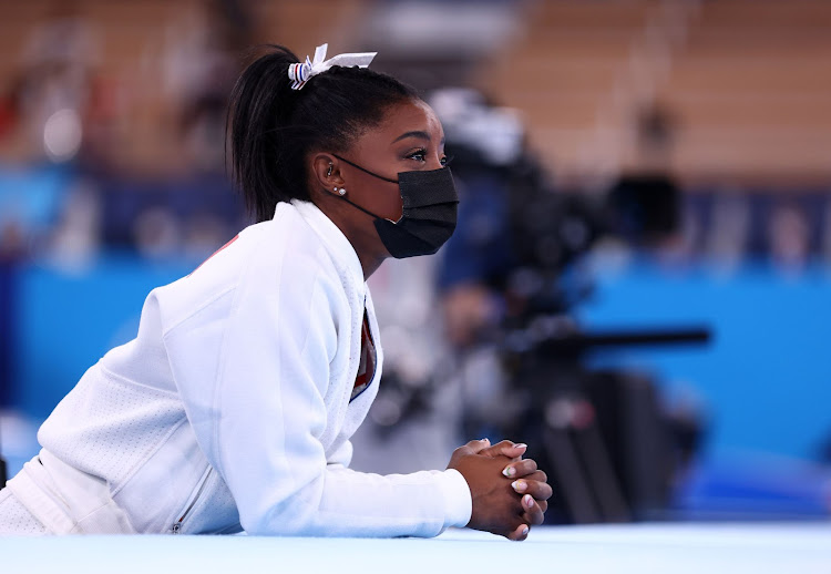 Simone Biles of the United States wearing a mask watches her teammates.