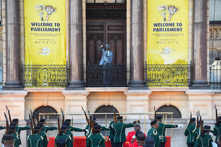 Members of the South African National Defence Force stand in line as a statue of forme president Nelson Mandela is visible on a balcony ahead of the state of the nation address by President Cyril Ramaphosa at the Cape Town City Hall on February 8 2024.