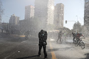 Antigovernment protesters are sprayed by a water cannon in Santiago, Chile. 