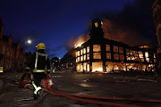 A firefighter walks past a burning building in Tottenham, north London