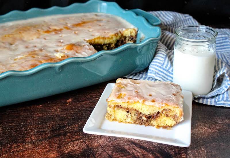 A Piece Of Honey Bun Cake On A Plate With A Glass Of Milk.