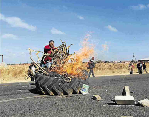 ENOUGH IS ENOUGH: A protester sets a tyre on fire on Mutare road outside Harare, Zimbabwe on Monday. In a protest over frequently blocked streets, operators of commuter buses themselves blocked roads with stones, burning tyres and other objects. Picture: EPA