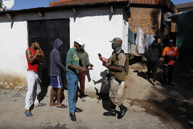 The army and police hand pamphlets to residents on the street of a densely populated Alexandra township in Johannesburg.