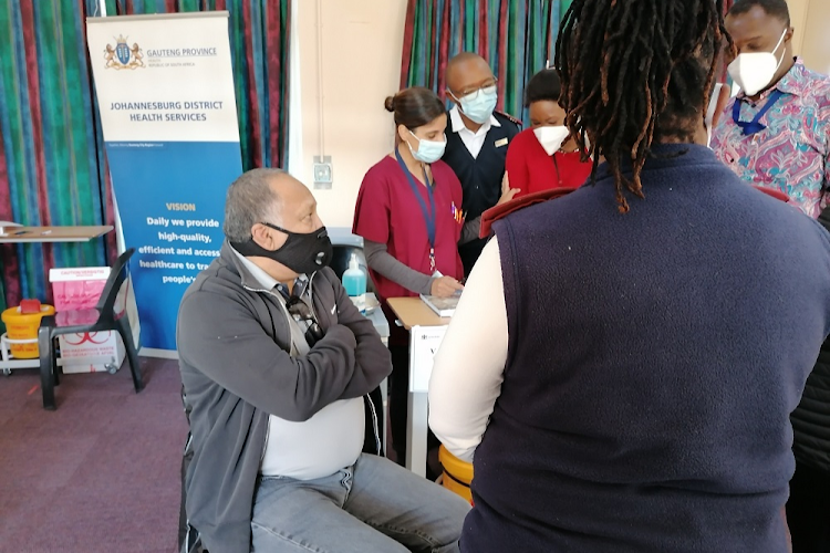 Tommy Harris waits to get his jab as nurses and staff at Discoverers Community Health Centre struggle to capture his details on the system.