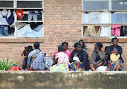 Displaced flood victims from Chiradzulu district sit outside a classroom at Montfort Primary School which is used as a temporary shelter after their homes were damage by mudslides and rockfalls in the aftermath of Cyclone Freddy.