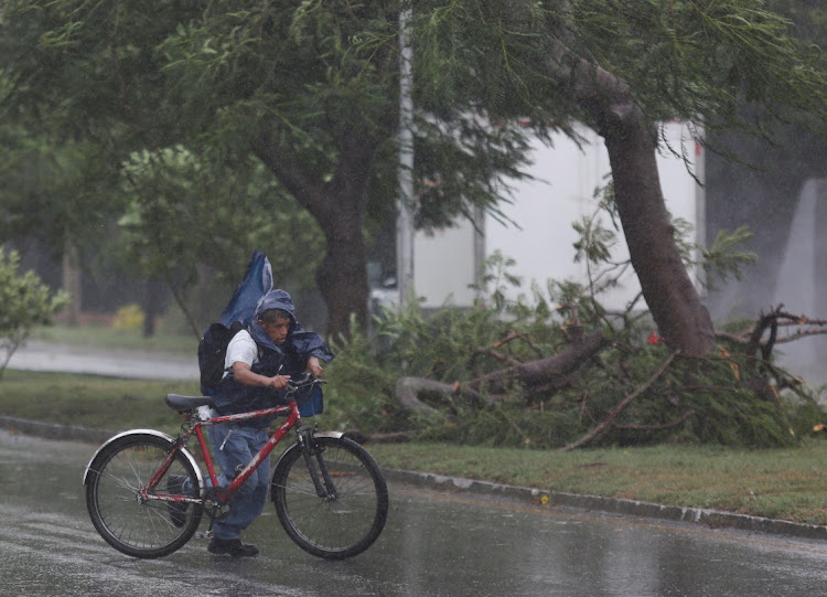 A man pushes his bike next to fallen tree branches after Hurricane Grace made landfall on the Yucatan Peninsula, in Merida, Mexico, on August 19, 2021.