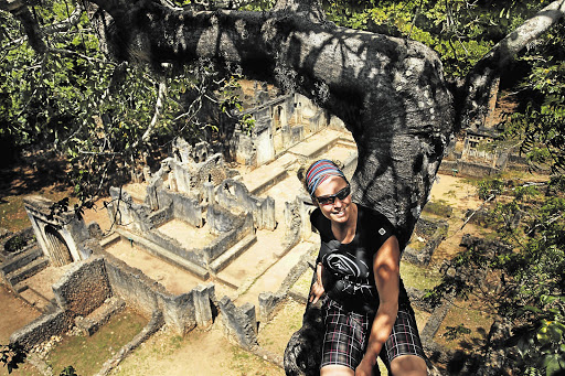 RUIN CLIMBING: Marianne Schwankhart sits high above the Gede ruins in the branches of a baobab tree