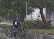 A man pushes his bike next to fallen tree branches after Hurricane Grace made landfall on the Yucatan Peninsula, in Merida, Mexico, August 19 2021.