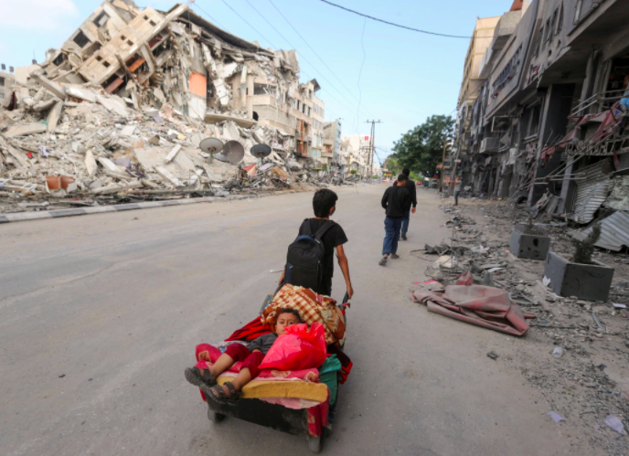 A Palestinian boy pulls a cart carrying his brother and their belongings as they fled their home during Israeli air and artillery attacks.