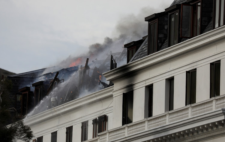 Flames and smoke rise from parliament buildings in Cape Town as the fire which started on Sunday flared up again on Monday. It has since been contained.