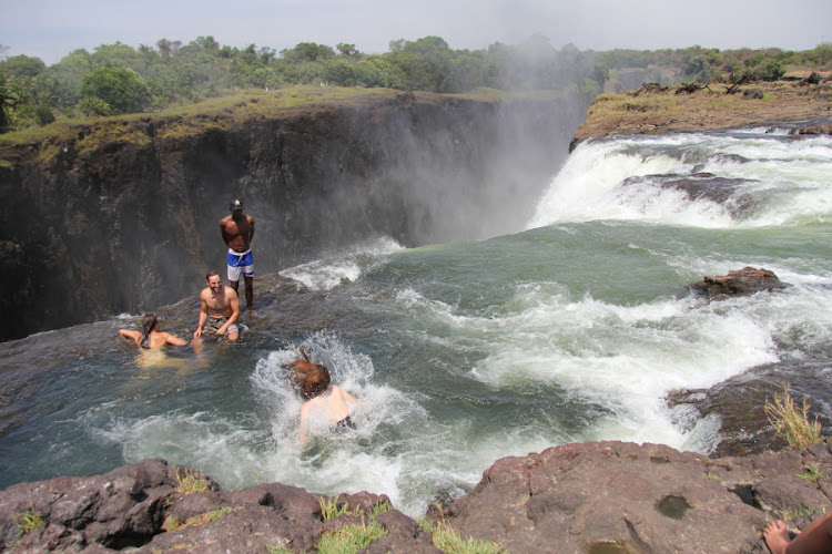 Tourists in the Devil's Pool, on the edge of the Victoria Falls.