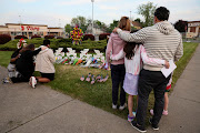 People look at a memorial at the scene of a weekend shooting at a Tops supermarket in Buffalo, New York, US May 19, 2022.  