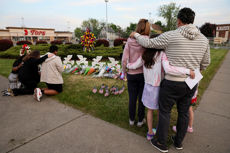 People look at a memorial at the scene of a weekend shooting at a Tops supermarket in Buffalo, New York, US May 19, 2022.