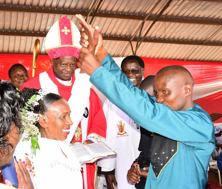 A couple showing its wedding ring as ACK Mt Kenya South Rt. Rev Canon charles Muturi looks on.