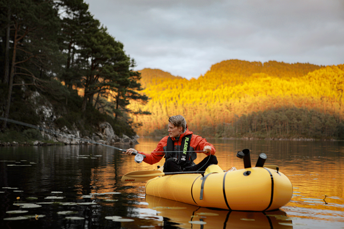 Tester fiskelykken fra packraften. Mann sitter i packraft, på et vann, fluefisker