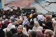 Palestinians gather to receive aid outside a warehouse as Gaza residents face crisis levels of hunger, amid the ongoing conflict between Israel and Palestine.