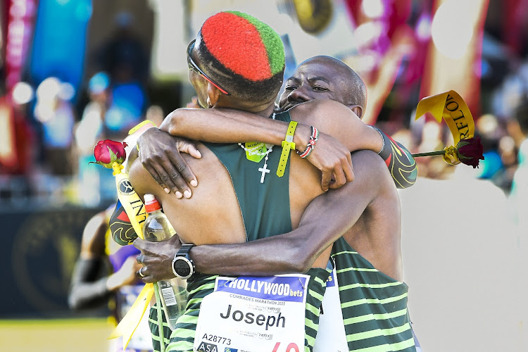 Tenth-placed Joseph Manyedi is embraced by third-placed Edward Mothibi at the finish.