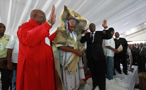 ANOINTED: AmaMpondo King Zanozuko Tyelovuyo Sigcau, centre, wears a lion’s skin after being enrobed by Chief Apostle Dr Caesar Nongqunga, right, in the black suit, with the assistance of Bishop Joseph Sigqibo Kobo, left Picture: LULAMILE FENI