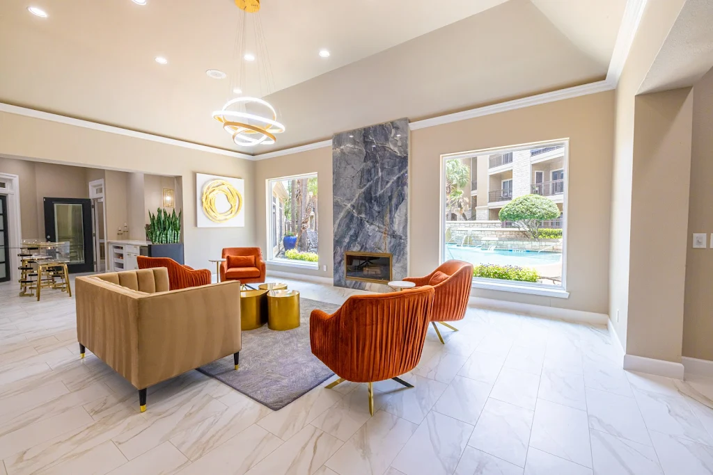 Clubhouse seating area with orange upholstered chairs, stone flooring and a marbled stone fireplace