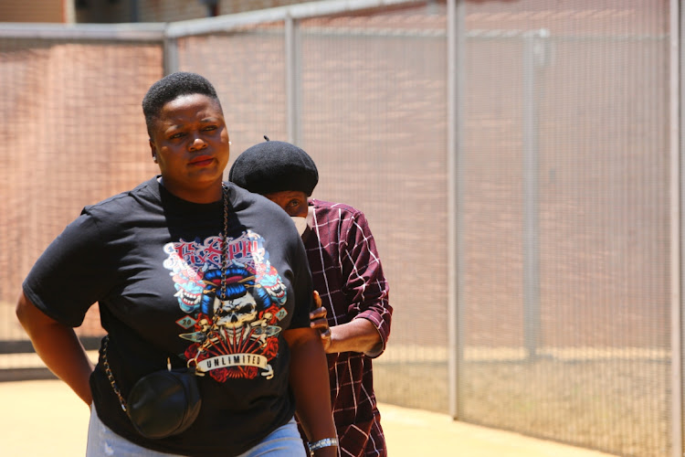 Pensioner Salamina Khoza hides behind a family member while leaving the Pretoria North magistrate's court after her fraud and perjury case was postponed to March next year.