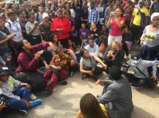 Rhodes University vice chancellor Sizwe Mabizela sits in a circle with protestors in the street