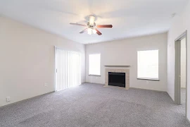 Living room with carpet, a fireplace, ceiling fan, and sliding door to the outdoor patio