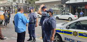 Police officers attend to a crime scene in Cape Town's city centre after armed robbers stole cigarettes worth tens of thousands of rands on May 7 2020.