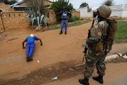 A policeman instructs a man to do push-ups during an operation in Eldorado Park on the fourth day of a nationwide coronavirus lockdown.