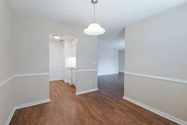 Dining Room with wood inspired floors, pendant light and light walls with a view to the kitchen entry and living room.