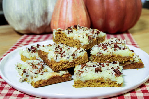 A stack of pumpkin cream cheese bars on a white plate.